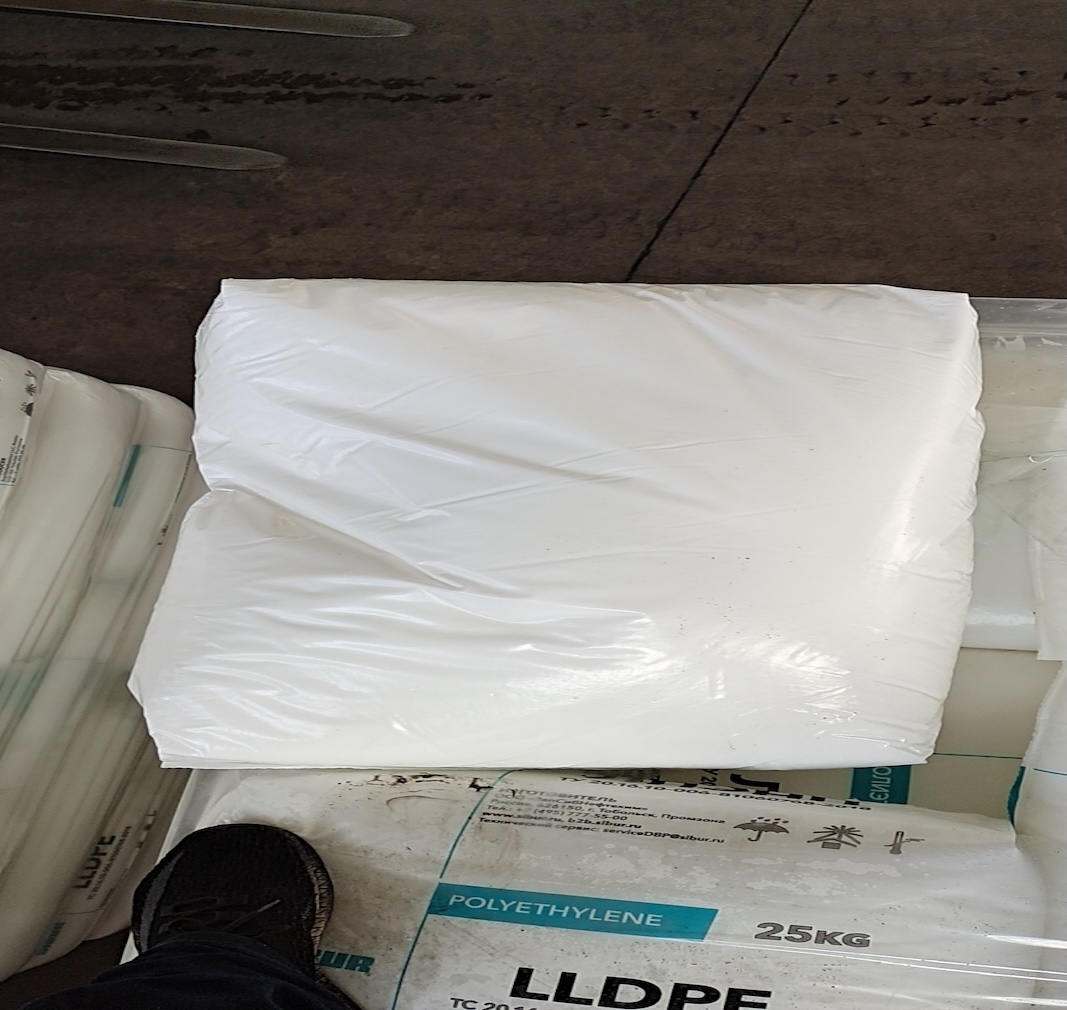 95a3e76d-8e9c-43ad-ab9b-55abe8924f91_Single wrapped Sibur LLDPE 25kg polyethylene resin sack laid on stacked plastic raw material bags warehouse floor.jpg
